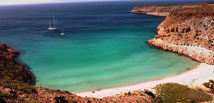 an isolated beach with two sailboats