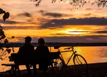 Couple sitting together on a bench watching the sunset, while enjoying the benefits of the Belize QRP Program.