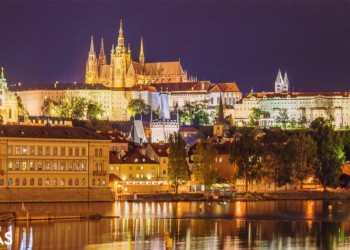 the Prague skyline by the river lit up at night