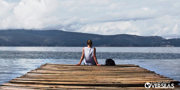 a woman with a backpack sitting at the end of a dock