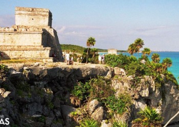 tourists visit stone ruins on a cliff in tulum