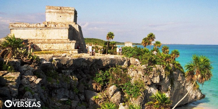 tourists visit stone ruins on a cliff in tulum
