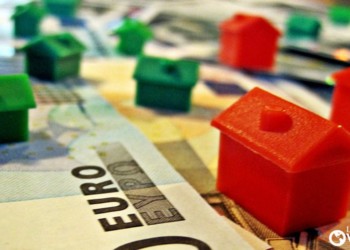 plastic red and green miniature houses on euro bills