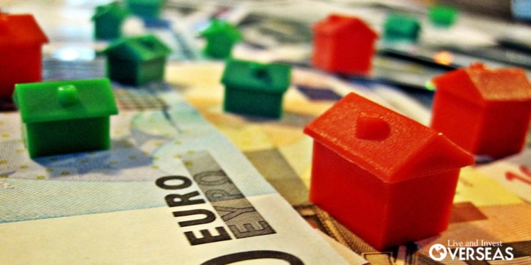 plastic red and green miniature houses on euro bills