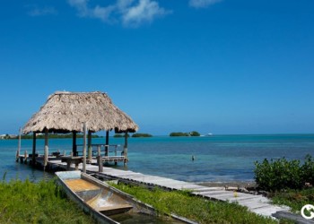 a wooden dock leading out to a thatched roof cabana over the ocean