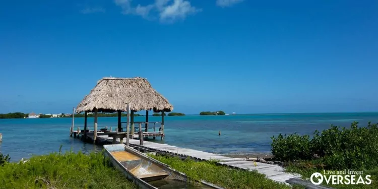 a wooden dock leading out to a thatched roof cabana over the ocean