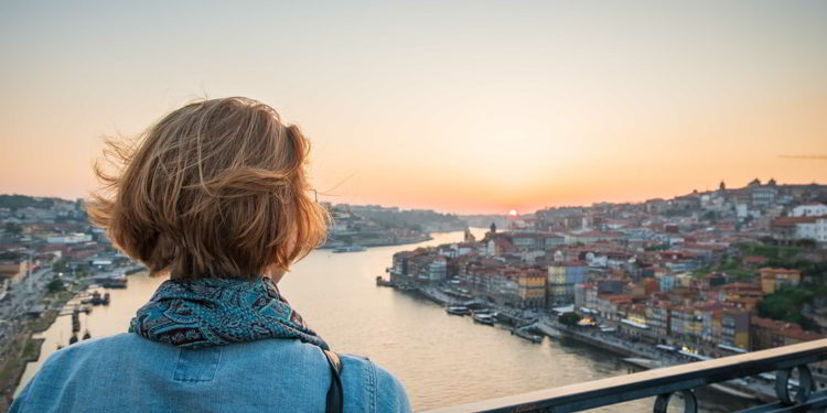 Redhead woman observing the sunset in Porto, Portugal on the bridge over the river