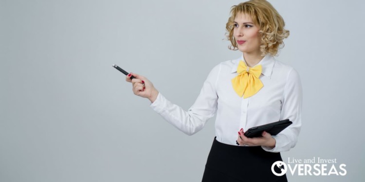 a blond woman wearing a white button down shirt and yellow bowtie holding a tablet