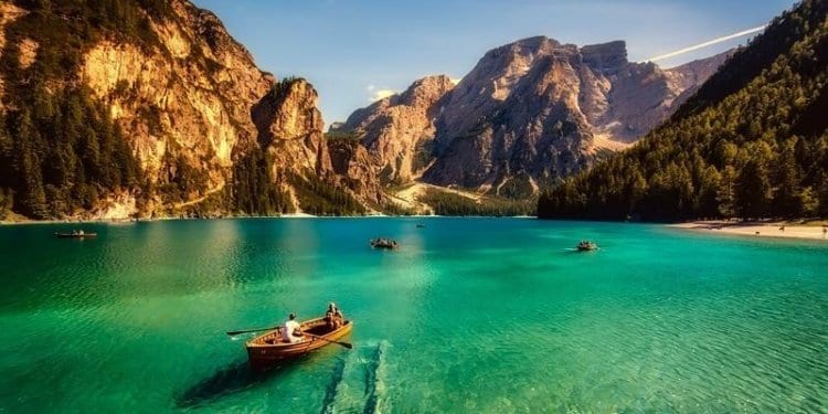 Rowing boats on a clear lake in Italy. Rocky mountains border the lake