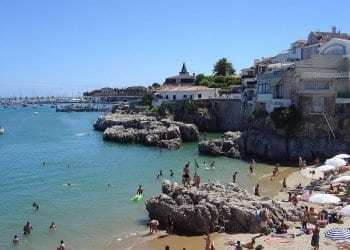 cascais, people swimming on a sandy and rocky beach in cascais portugal