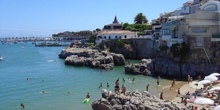 cascais, people swimming on a sandy and rocky beach in cascais portugal