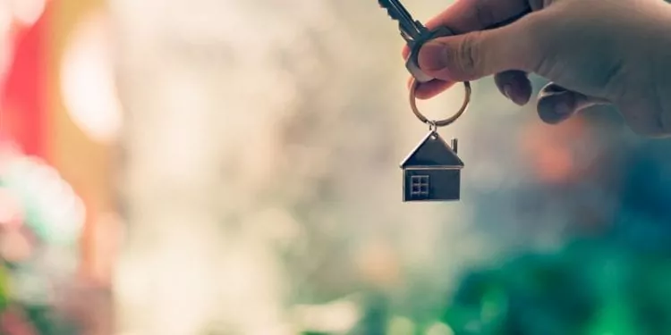 A hand holding a key with house keyring