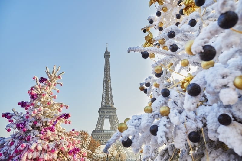 Decorated Christmas trees covered with snow near the Eiffel tower in Paris, France.