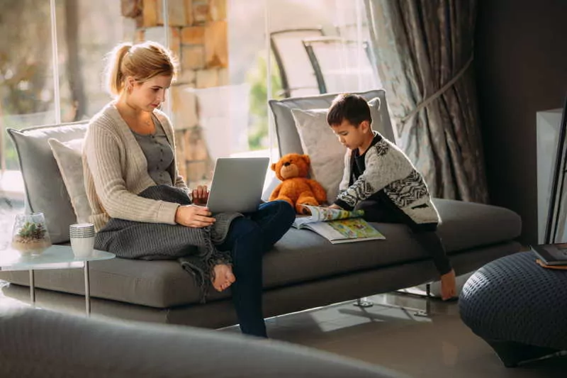 mother working from home while son plays on tablet