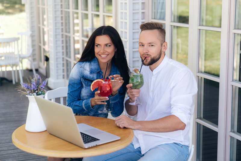 a couple working together on their laptops having some cocktails