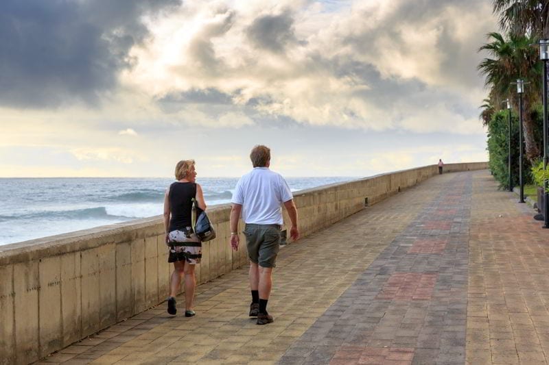 Senior couple walking on the boulevard in the evening at sunset, on the island Madeira, Portugal