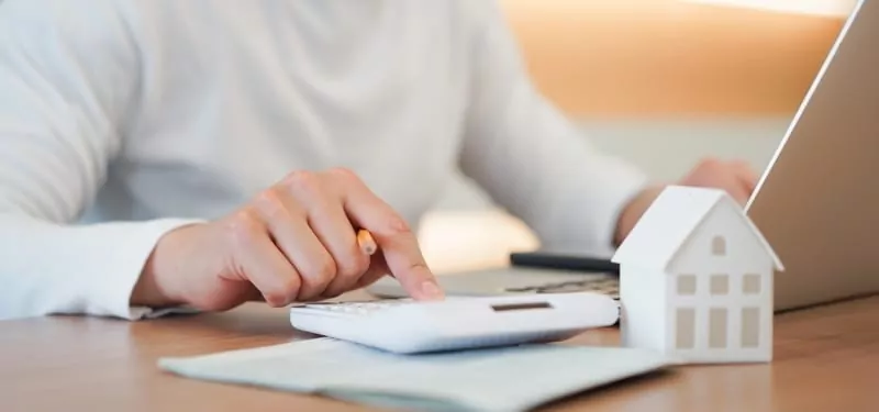 Man hand press on calculator to check expense of home loan mortgage. Buying property overseas concept.