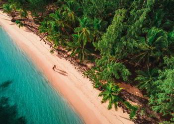 Two people walking on a white sand beach in Dominican Republic