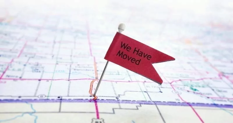 Closeup of red pin flag on a map with We Have Moved text