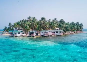 View of Tobacco Caye small Caribbean island with palm trees and bungalows in the Belize Barrier Reef