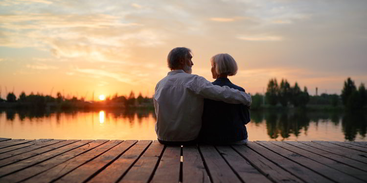 Senior couple sitting together on lake bank