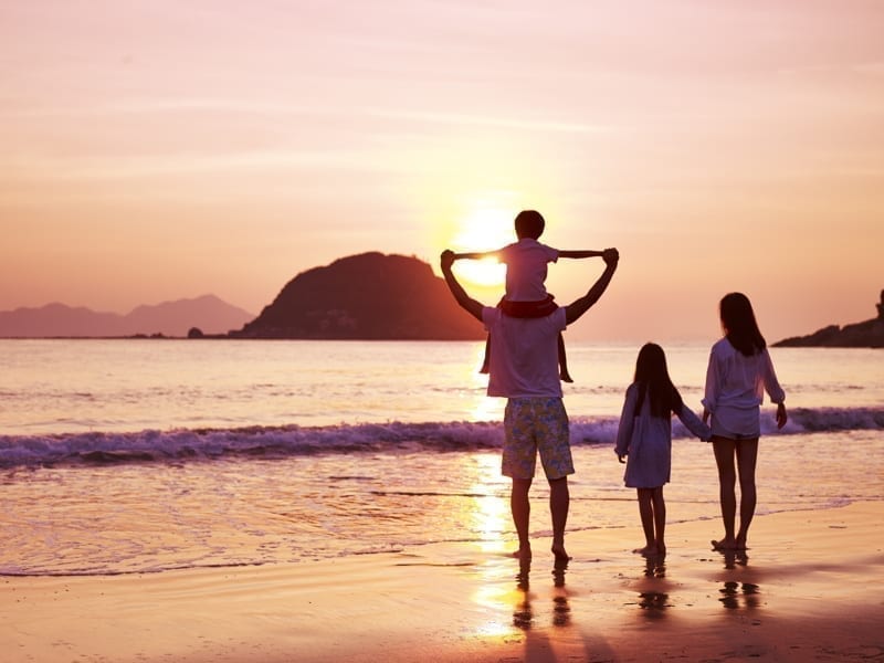 Family watching sunrise on beach.