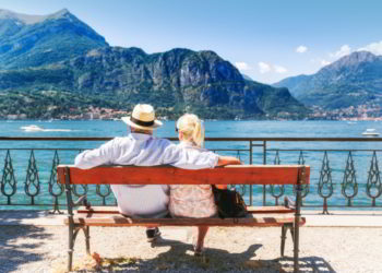 A couple sitting on a bench enjoying a sunny day at a lake