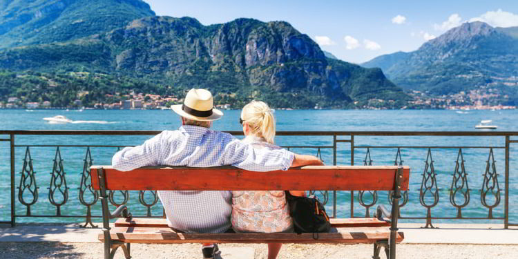 A couple sitting on a bench enjoying a sunny day at a lake