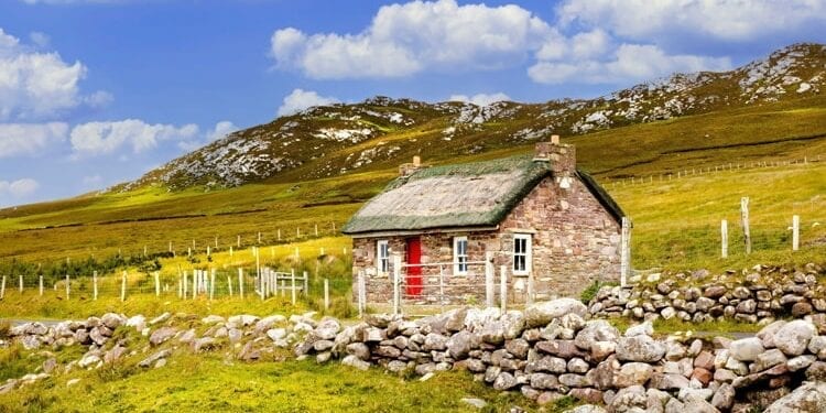 Traditional Irish thatched cottage and stone wall or fence on Achill Island in County Mayo Ireland