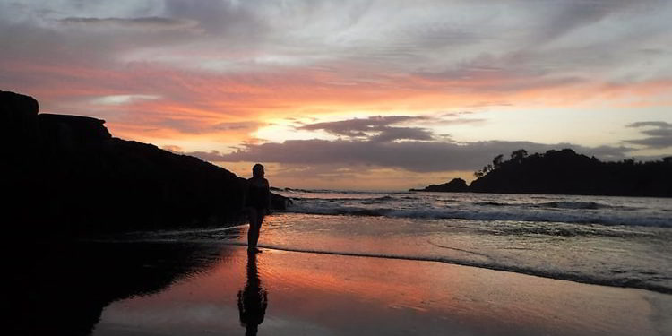 A person standing on a beach during sunset in Los Islotes, Panama
