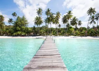 Paradise beach with turquoise water, wooden pier and tropical palm trees, summer holidays in Thailand. Plan Your Retirement Overseas