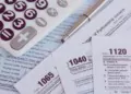 Calculator, pen on US tax form background