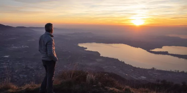Hiker looking sun over horizon