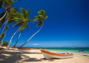 Paradise beach with fishing boats, white sand, palm trees and blue water of Atlantic Ocean, Las Terrenas, Samana. Live In The Dominican Republic