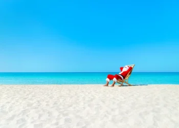 Christmas Santa Claus resting on sunlounger at ocean sandy tropical beach
