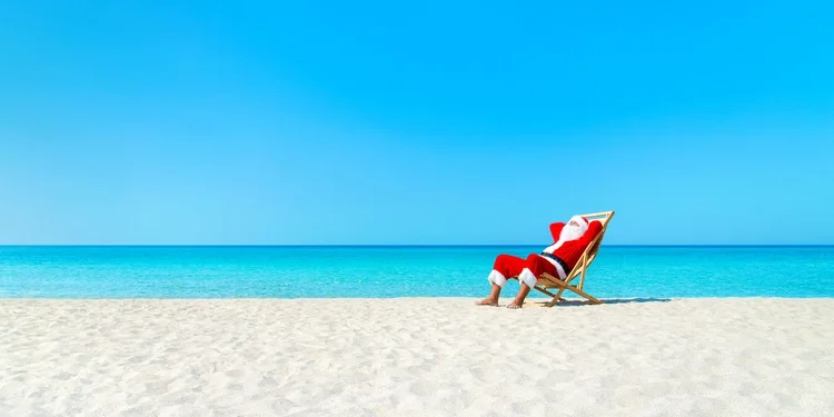 Christmas Santa Claus resting on sunlounger at ocean sandy tropical beach