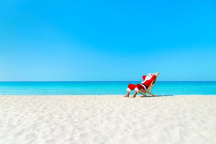 Christmas Santa Claus resting on sunlounger at ocean sandy tropical beach