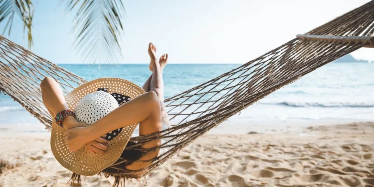 Traveler woman relaxing in hammock on summer beach Thailand